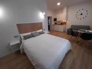 a bedroom with a large white bed and a couch at Apartamentos Recunchos in Ourense