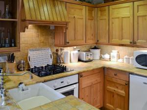 a kitchen with wooden cabinets and a stove top oven at Mushroom Cottage in Castleton