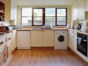 a kitchen with a sink and a washing machine at Swallows Cottage in Tipton Saint John