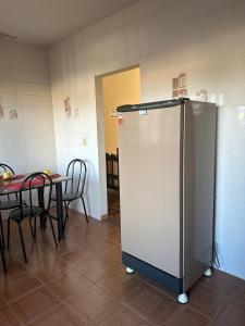 Una cocina con una mesa y un refrigerador en una habitación. en Edifício solar de Piuma, en Piúma
