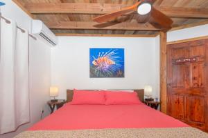 a bedroom with a red bed with a ceiling fan at West Bay Unique Home with an amazing oceanview in West Bay +37 photos
