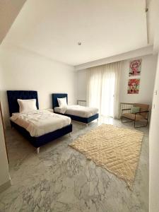 a bedroom with two beds and a rug at Le somptueux du lac 2 in El Aouina Station