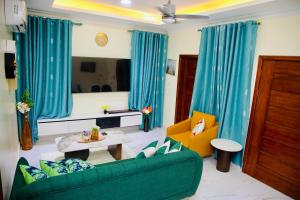a living room with blue curtains and a green couch at GreyCity Apartments in Accra
