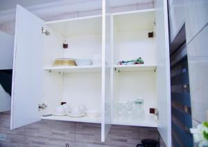 a white cabinet with cups and dishes in it at GreyCity Apartments in Accra +53 photos