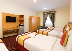 a hotel room with three beds and a television at فندق رفاق مكة in Makkah +56 photos