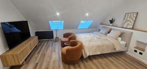 a bedroom with a bed and two chairs and a television at La suite Cherbourgeoise in Cherbourg en Cotentin