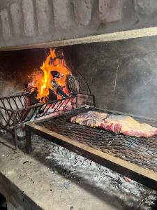 un pezzo di carne che cuoce su una griglia con fiamme di La Alpina a Chivilcoy Altre 14 foto