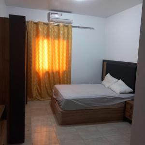 ein Schlafzimmer mit einem Bett und einem orangenen Vorhang in der Unterkunft Sicap baobab , Mermoz, Sacré Coeur , Clim, Wifi, Balcon, Dakar in Grand Dakar