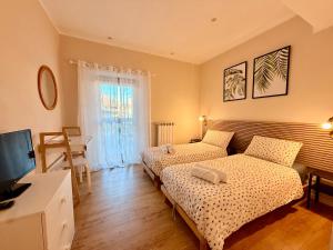 a bedroom with two beds and a tv and a window at Casa Kiara by KALMA in Domodossola
