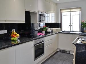 a kitchen with white cabinets and black counter tops at Beacon Cottage in Ivybridge