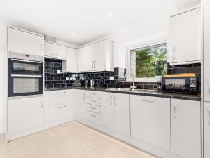 a white kitchen with white cabinets and a window at Seaborne Cottage - Pwlheli in Pwllheli