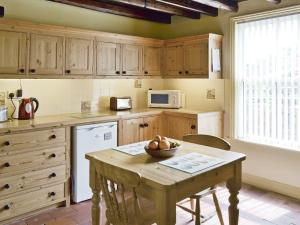 a kitchen with a table with a bowl of fruit on it at West End Farmhouse in Barmston +14 photos