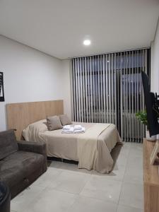 a bedroom with a bed and a couch and a window at Bonhomía Bim Tower in Neuquén +26 photos