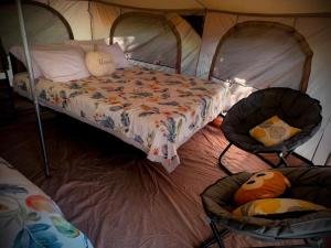 a bedroom with a bed and two chairs in a tent at Sloth Glamping & Villas Fortuna in San Francisco