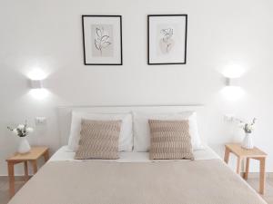 a white bedroom with two pictures above a bed at DoMe Affittacamere in Iglesias