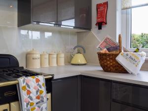a kitchen counter with a stove and a basket on it at Bumble Lodge in Llynclys +4 photos