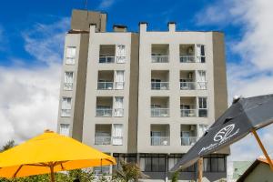 a tall building with an umbrella and a yellow umbrella at Palm Beach Apart Hotel - Pé na Areia in Florianópolis