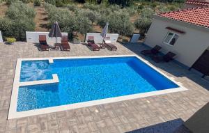 a swimming pool with chairs and a house at Beautiful Apartment In Sukosan in Donje Raštane