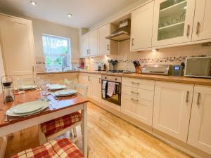 a kitchen with white cabinets and a wooden table at 2 Greta Grove House in Keswick