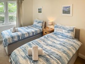 a bedroom with two beds and a window at 2 Greta Grove House in Keswick