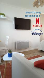 a living room with a couch and a tv on a wall at L'Escale Songeonnaise in Songeons