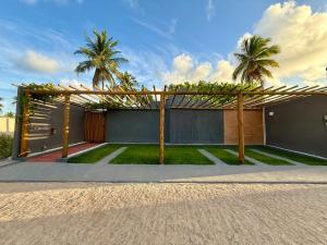 a house with a pergola on the side of it at Bangalô Miramar Maragogi in Maragogi