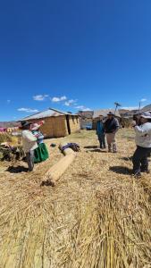Un grupo de personas de pie en un campo de heno en Titicaca Floating Lodge, en Puno