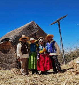 un grupo de personas de pie en frente de una cabaña en Titicaca Floating Lodge, en Puno