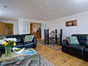 a living room with black leather couches and a table at Fistral View At Bredon Court in Newquay