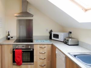 a kitchen with a stove top oven next to a microwave at Ysgubor Uchaf - 29517 in Fairbourne