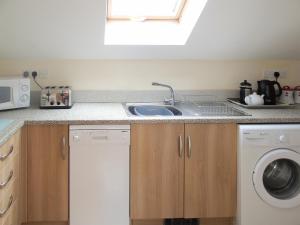 a kitchen with a sink and a washing machine at Ysgubor Uchaf - 29517 in Fairbourne +14 photos