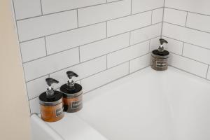 a white tiled bathroom with three bottles on a tub at Near Downtown & Waterfront, AC, Pet Friendly in Tacoma +76 photos