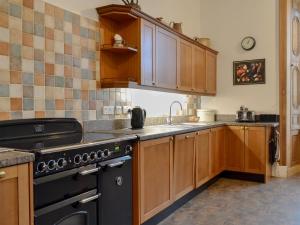 a kitchen with wooden cabinets and a black stove at The Factors House - 25752 in Kilmartin