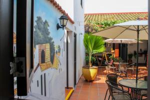 a patio with tables and chairs and an umbrella at Hotel Colonial San Felipe in Girón