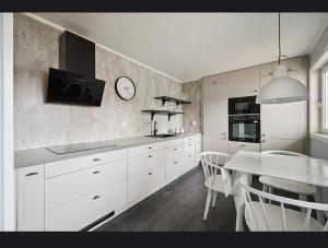 a kitchen with white cabinets and a table and a clock at Apartment in central Kirkenes in Kirkenes