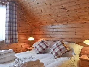 a bedroom with a bed in a wooden wall at Wee Ben in Bridge of Tilt