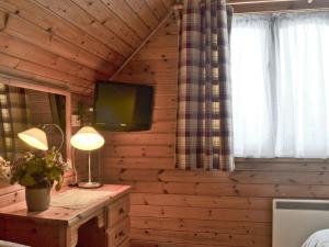 a bedroom with a wooden wall with a tv and a desk at Wee Ben in Bridge of Tilt