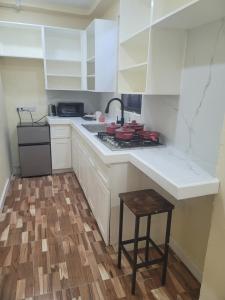 a kitchen with white cabinets and a stove and a stool at Midtown in Saint Georgeʼs +11 photos