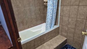 Un baño con ducha y bañera. en Cabañas La Catarata, en Higueronal