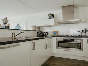 Una cocina blanca con fregadero y estufa. en Apartment in Netherlands near Amsterdam, en Uitgeest