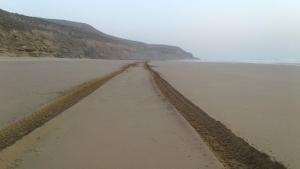 a tire track in the sand on a beach at Chezidar Tafadna Essaouira 