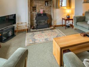 a living room with a fireplace and a couch and a table at Holly Bank in Crich