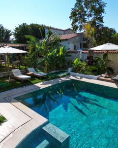 a swimming pool in a yard with chairs and umbrellas at naya port in Alacati