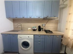a kitchen with blue cabinets and a washing machine at Studio Bella Centru 26 in Craiova