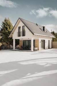 a white house with black windows and a driveway at BURSZTYNOWA-PRZYSTAŃ in Lubiatowo