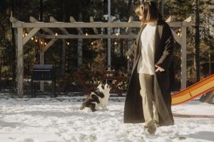 a woman walking a dog in the snow at BURSZTYNOWA-PRZYSTAŃ in Lubiatowo