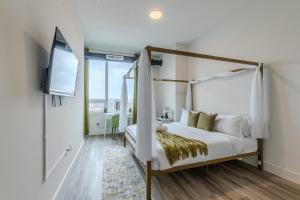 - une chambre avec un lit à baldaquin et une télévision dans l'établissement Emerald Escape, Free Parking, 2 Bath, Sleeps 8 Near American Dream and The Airport, King Bed and 2 Queen Beds, Washer and Dryer, à Orange
