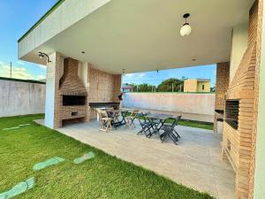 eine Terrasse mit einem Tisch, Stühlen und einem Kamin in der Unterkunft Casa com 2 suites em condomínio no Frances in Marechal Deodoro