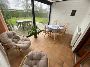 a screened in patio with a table and chairs and a table at Domein 15 De Haan Nieuwmunster, 4-bedroom holiday house for up to 6 people, between Wenduine, 1 km, and De Haan, 2 km, 500 meters from the beach,15 min from Bruges, Ostend and Knokke, nice fenced garden, no services offered in Zuienkerke