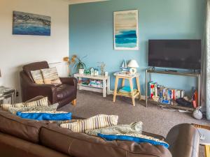 ein Wohnzimmer mit einem braunen Sofa und einem TV in der Unterkunft Turnstone - 2 Linden Court in Brixham